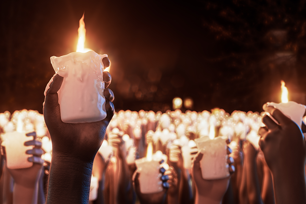 A hand holds up a lit candle during a candlelight vigil